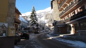 A snow-covered street with buildings, a Christmas tree, and a mountain in the background. - 4-room apartment, South facing, 6 people, pets allowed (Valloire)