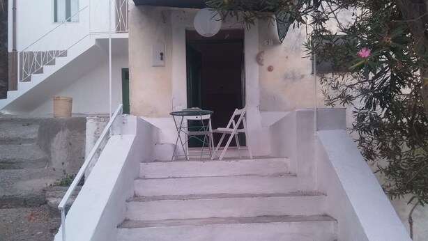 A set of white stairs leading to a building entrance with a small table and chairs outside.