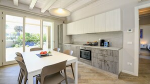 Una cocina moderna con armarios blancos, una isla grande y un área de comedor con sillas.