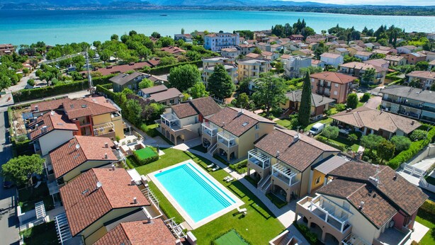 Una zona residencial con una piscina rodeada de casas con techos de tejas rojas.