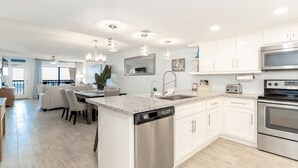 A modern kitchen with white cabinets, stainless steel appliances, and a granite countertop. - Saida III 1105 (3115) - Coastal 2 bedroom Condo for 6 guests in Beachfront Resort with 3 pools and amazing View (South Padre Island)