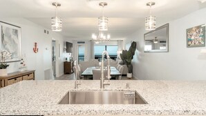 A modern kitchen with granite countertops, stainless steel appliances, and pendant lighting. - Saida III 1105 (3115) - Coastal 2 bedroom Condo for 6 guests in Beachfront Resort with 3 pools and amazing View (South Padre Island)