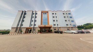 Un hôtel à plusieurs étages, doté d’une entrée principale, d’un parking et offrant une vue sur un ciel dégagé.