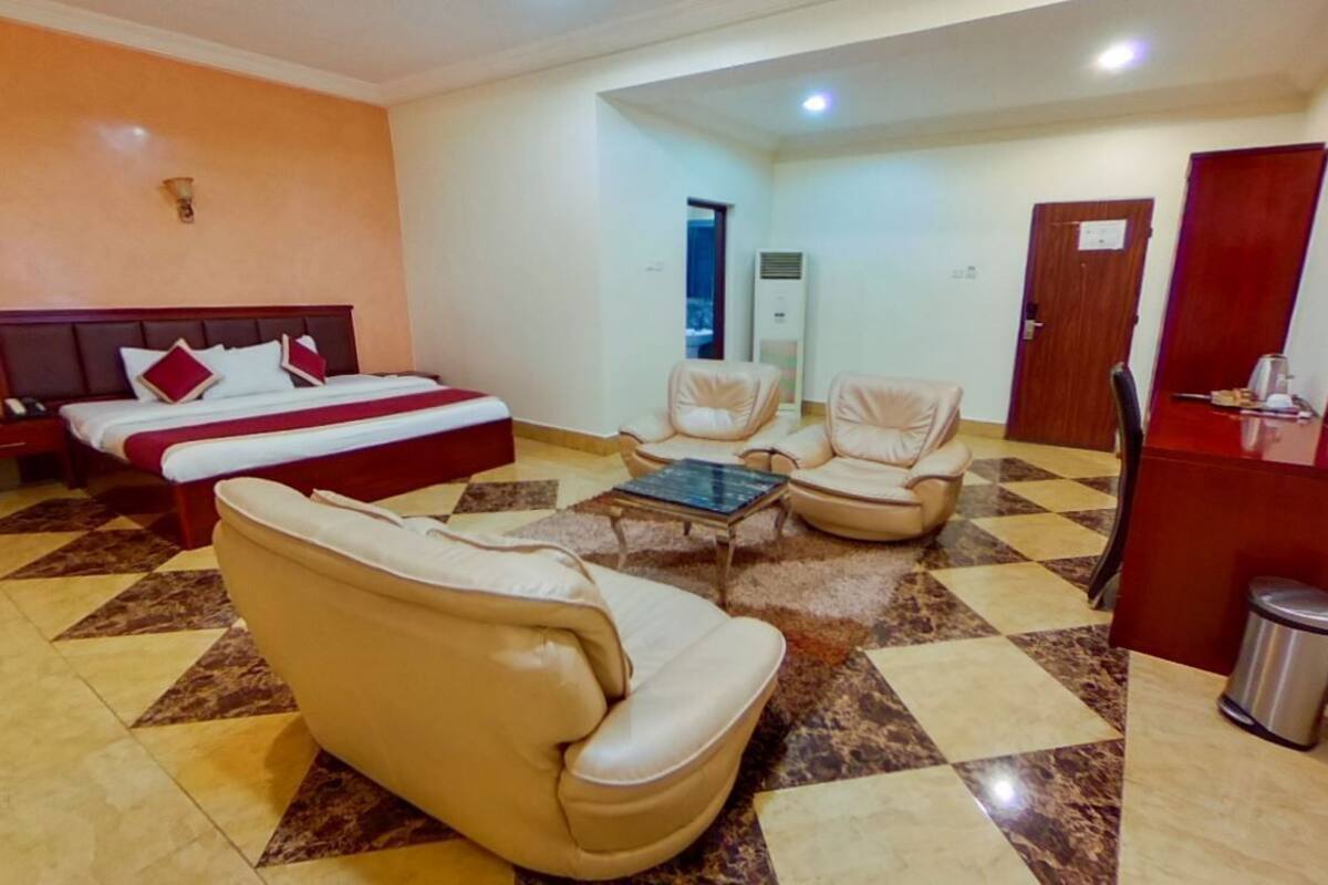 A hotel room with two beds, a sofa, a chair, a small table, and a TV.