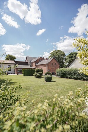 A brick building with a sloped roof, surrounded by a well-maintained lawn and hedges. - Gasthof Zum Goldenen Stern (Karstädt)