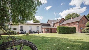 Un patio con césped, un edificio de ladrillo y un edificio blanco con balcón.