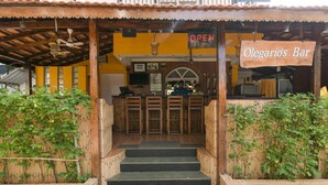 A wooden bar with a sign reading "Olegario's Bar" and a "OPEN" sign above the entrance.