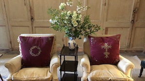 Two armchairs with floral cushions, a small table with a vase of flowers, and a glass table with candles and fruit. - Explore an entire castle whilst staying in historical splendour. (Peebles)
