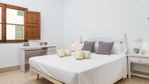 Ein Schlafzimmer mit Bett, Nachttischen, einem Schreibtisch und einem Fenster mit Fensterläden.