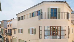 Ein zweistöckiges Gebäude mit Balkon, großen Fenstern und Fensterläden.