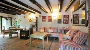 A cozy living room with a fireplace, striped sofa, and a dining area with a table and chairs. - Historical country house Costa Brava | Dali 2 Pax (Vilanant)