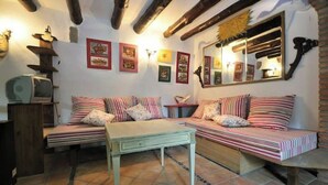 A cozy living room with a sofa set, a small table, and a television. - Historical country house Costa Brava | Dali 2 Pax (Vilanant)