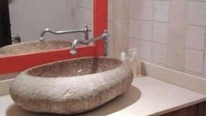 A bathroom with a stone sink, a red-framed mirror, and wooden cabinets. - Historical country house Costa Brava | Dali 2 Pax (Vilanant)