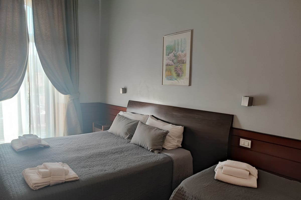 Habitación de hotel con dos camas, un cuadro en la pared y una ventana con cortinas.