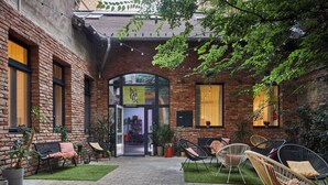 A brick building with a courtyard featuring a paved walkway, outdoor seating, and potted plants. - Butik Art Hotel (Budapest)
