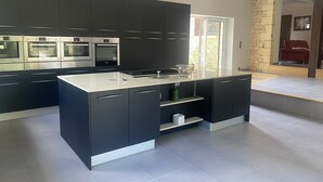 A modern kitchen with dark cabinetry, stainless steel appliances, and a large island. - Villa & Spa Heated pool Périgord 5 min from Sarlat (Sarlat-la-Canéda)