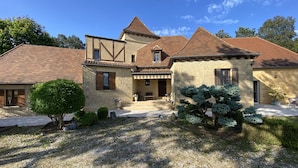 A stone house with a tiled roof, a porch, and a gravel driveway. - Villa & Spa Heated pool Périgord 5 min from Sarlat (Sarlat-la-Canéda)