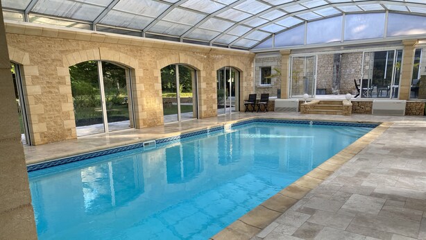 An indoor swimming pool with stone walls and a glass ceiling. - Villa & Spa Heated pool Périgord 5 min from Sarlat (Sarlat-la-Canéda)