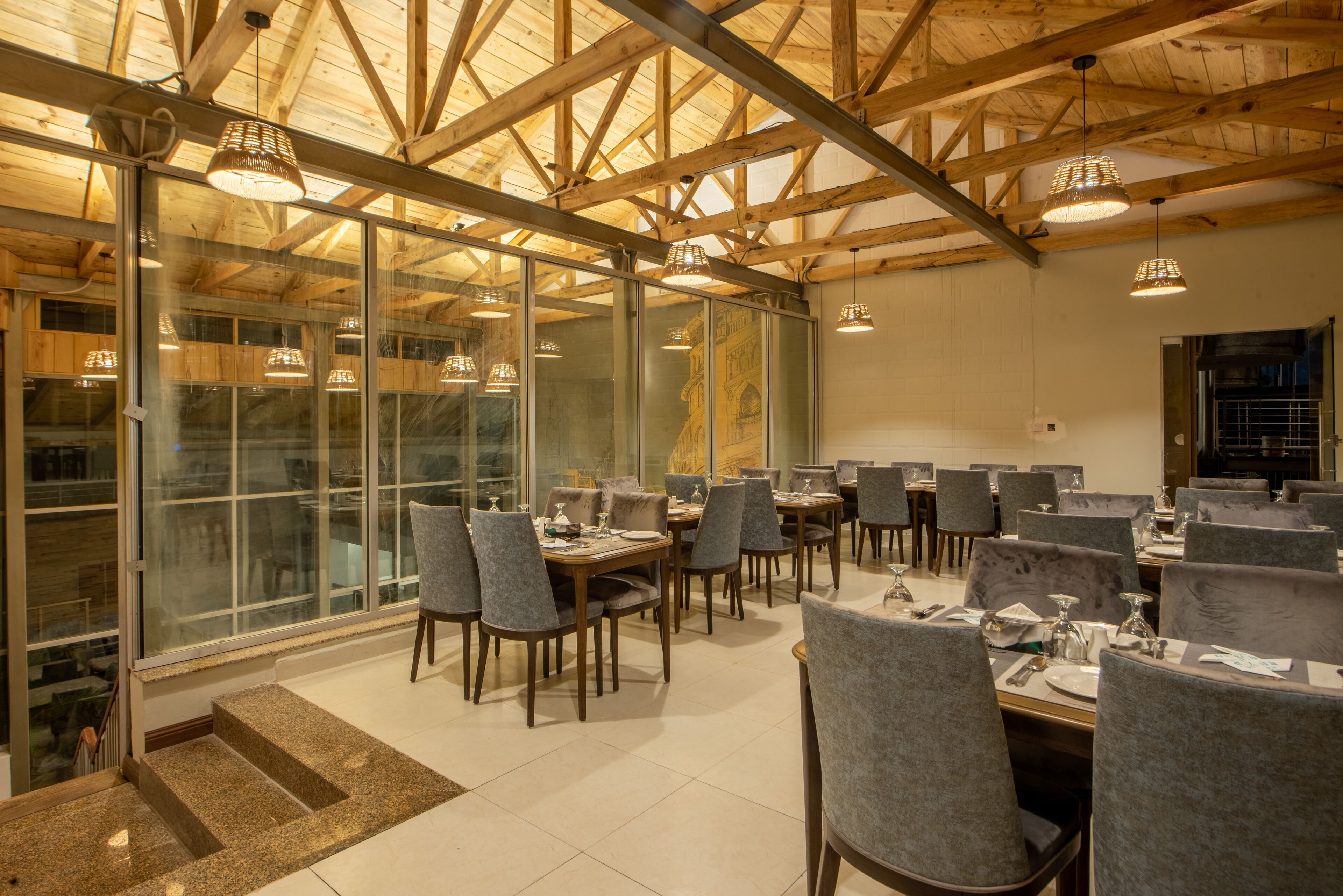 Un comedor con varias mesas y sillas, ventanas amplias y un techo alto con vigas de madera.