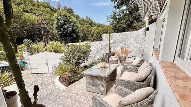 A patio area with wicker furniture, a stone floor, and a view of a lush garden. - House with spa surrounded by nature in Saint Paul de Vence (Saint-Paul-de-Vence)