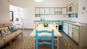 A compact kitchen with a dining table, chairs, and a refrigerator. - Villetta Anna Torre Suda (Racale)
