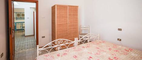Quarto com cama, guarda-roupa e uma cadeira.