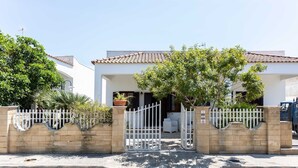 A gated residential property with a tiled roof, white walls, and a paved entrance. - Villetta Anna Torre Suda (Racale)