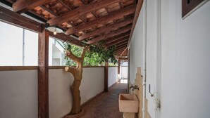 A covered corridor with a wooden ceiling, a stone planter, and a sink against the wall. - Villetta Anna Torre Suda (Racale)