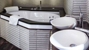 Un baño moderno con una bañera independiente, dos lavamanos y piso de madera.