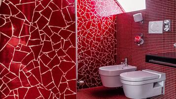Uma casa de banho moderna com paredes em mosaico vermelho e uma pia branca.