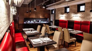Un interior de restaurante con cabinas y mesas, una zona de bar y una pared de piedra.