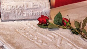 Una toalla de hotel con el nombre "HOTEL MARIBOR" estampado, sobre una cama con una rosa roja.