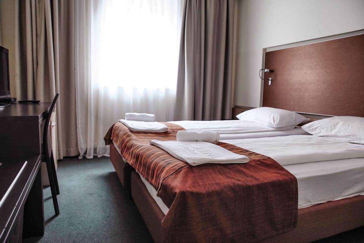 A hotel room with two beds, a desk, and a television.