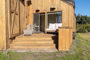 A wooden cabin with a porch, a sofa, and a chair. - Charlie's Retreat | Hot Tub & EV Charger (Sea Ranch)