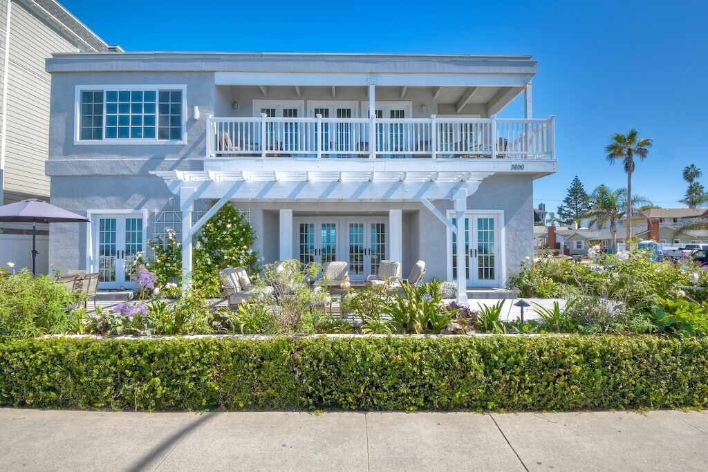 A two-story building with a balcony, large windows, and a well-maintained garden.