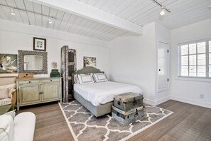 Une chambre à coucher avec un lit, une commode, un miroir et une fenêtre.