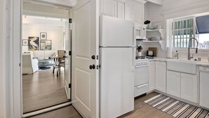 A modern kitchen with white cabinetry, a refrigerator, stove, and a sink. - Ocean View From Private Patio | Across From Beach (Carlsbad)