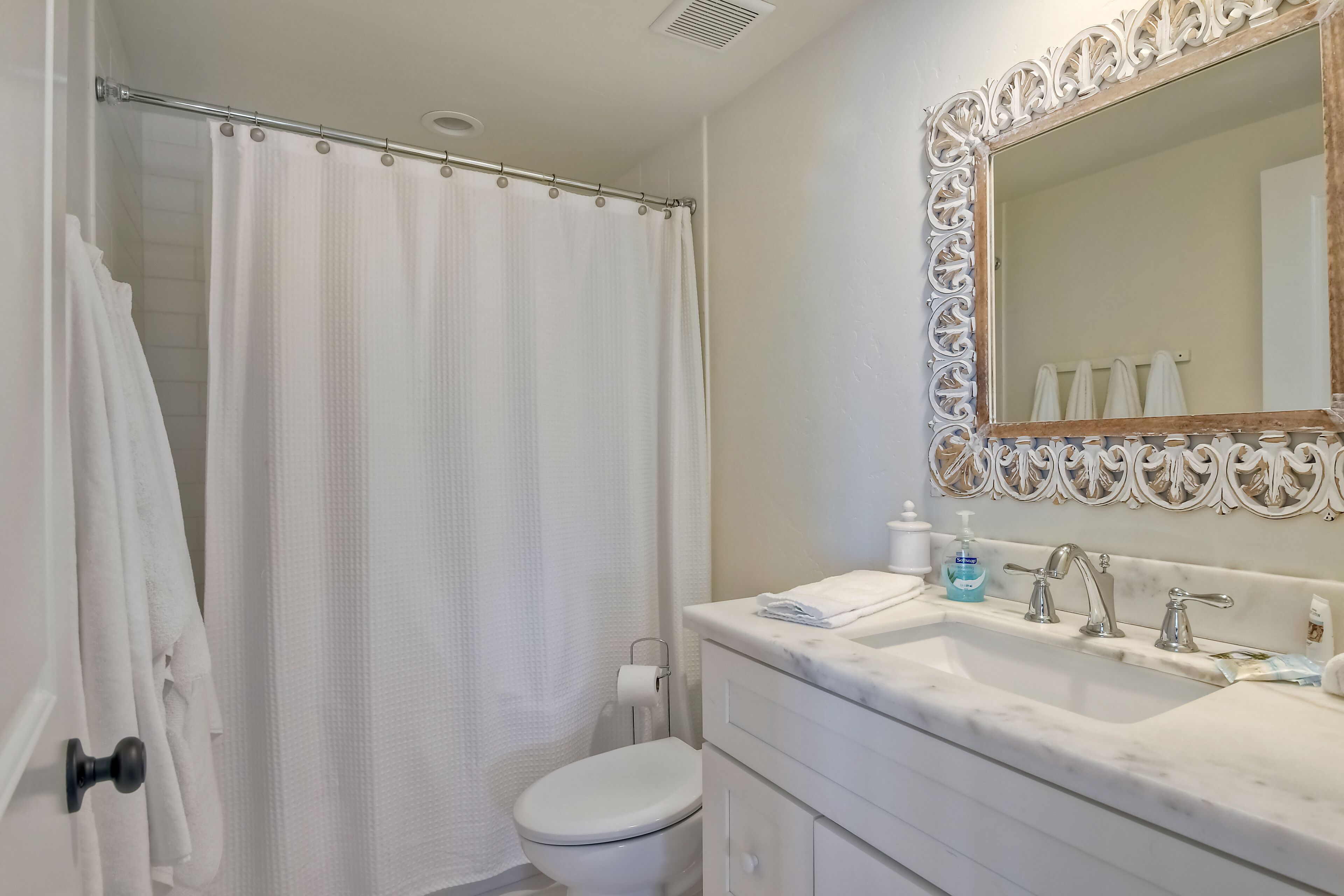 Une salle de bain équipée d’une douche avec rideau, de toilettes, d’un lavabo avec miroir et d’un porte-serviettes.