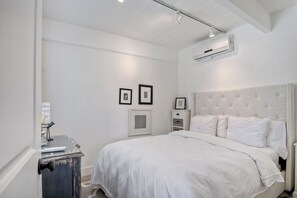 Un dormitorio con una cama grande, paredes blancas y un ventilador de techo.