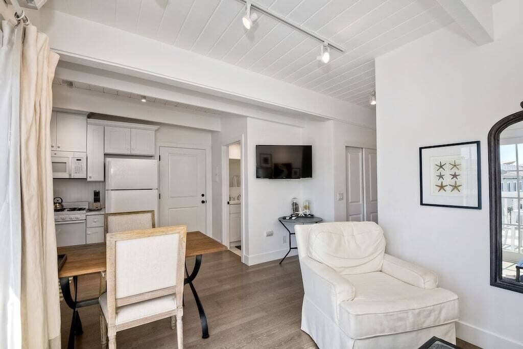 Une cuisine moderne avec des meubles blancs et un coin repas comprenant une table en bois et des chaises blanches.