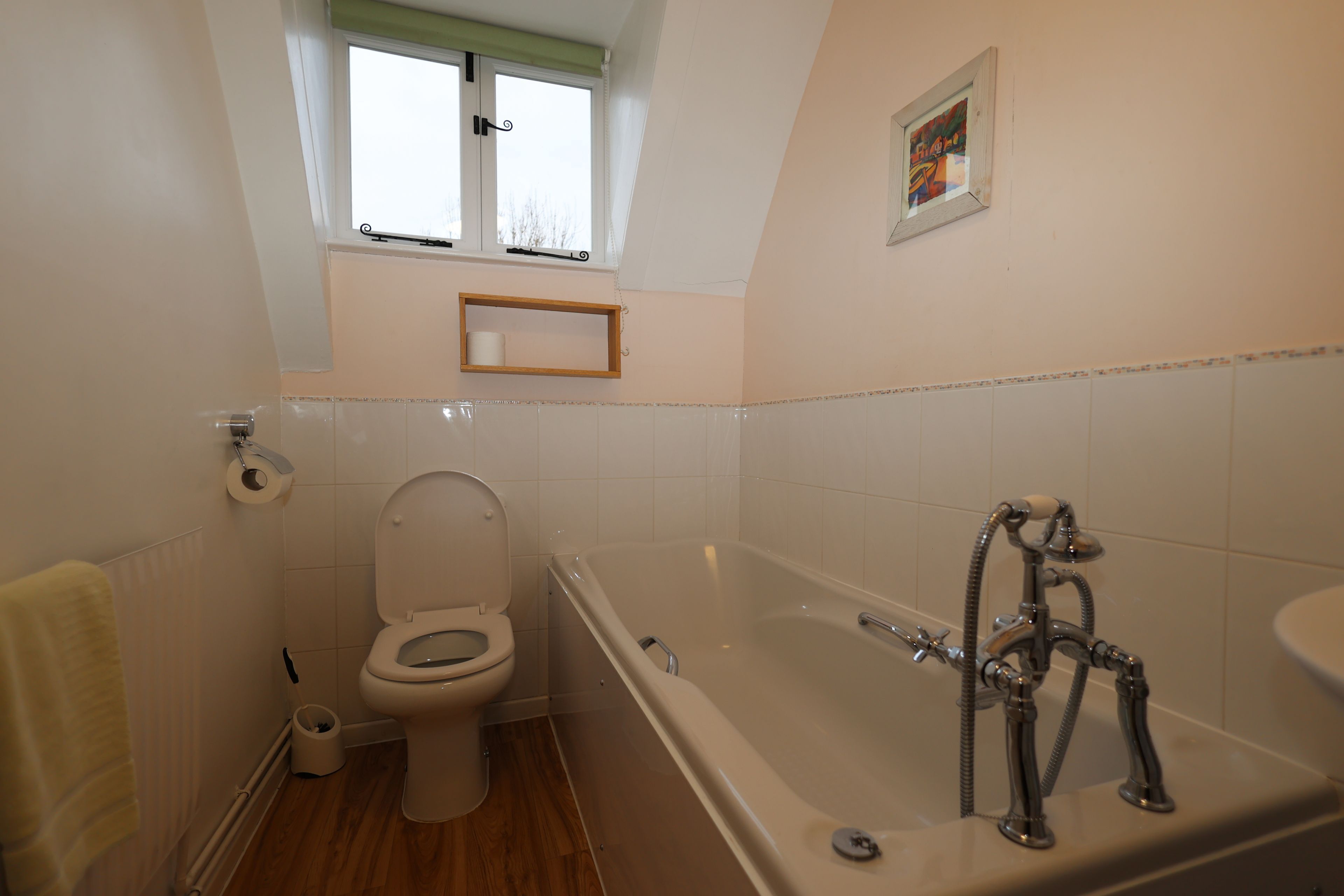 Une salle de bain avec des toilettes, une baignoire et une fenêtre située au-dessus des toilettes.