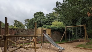 A playground with a slide, climbing structures, and a rope net.