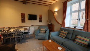 A cozy living room with a sofa, armchair, and dining table.