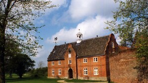 A large brick building with a central arched entrance, a bell tower, and a clock.