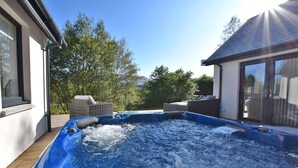 A hot tub in a backyard with a house and trees in the background. - Luxury Villa Near Ben Nevis, Scottish Highlands (Spean Bridge)