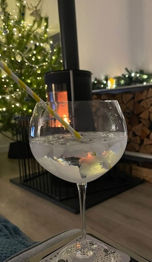 Un verre d’eau avec une paille, dans une pièce décorée d’un sapin de Noël et dotée d’une cheminée.