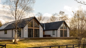 A modern two-story house with large windows and a sloped roof. - Luxury Villa Near Ben Nevis, Scottish Highlands (Spean Bridge)