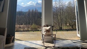 A spacious room with a high ceiling, large windows, and a mountain view. - Luxury Villa Near Ben Nevis, Scottish Highlands (Spean Bridge)