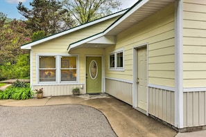 Stunning residential building with a green front door, flanked by two windows, set amidst lush greenery.