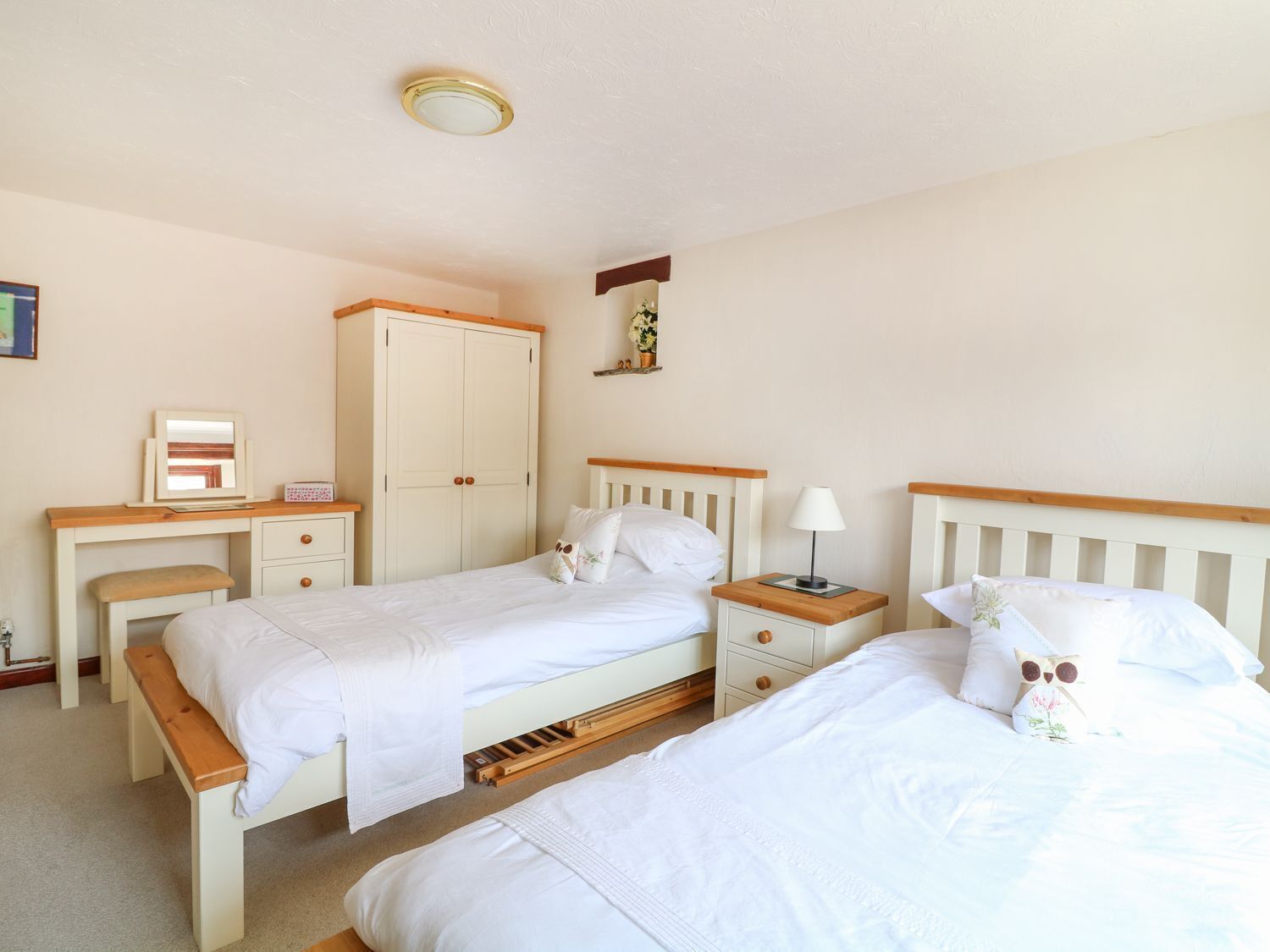 A bedroom with two beds, a desk, a wardrobe, and a bedside table.